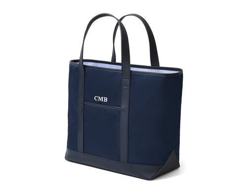 The Treadwell Tote: Navy Ballistic -White Embroidery, featuring a navy canvas body, leather handles, front pocket with CMB, and striped lining.