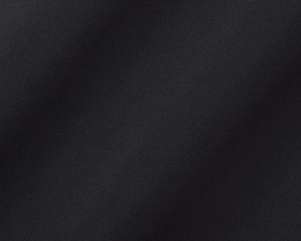 The Farrell Shirt: Black, close-up of textured performance jersey fabric with subtle folds, featuring long sleeves, spread collar, and contrast piping for versatile comfort and style.