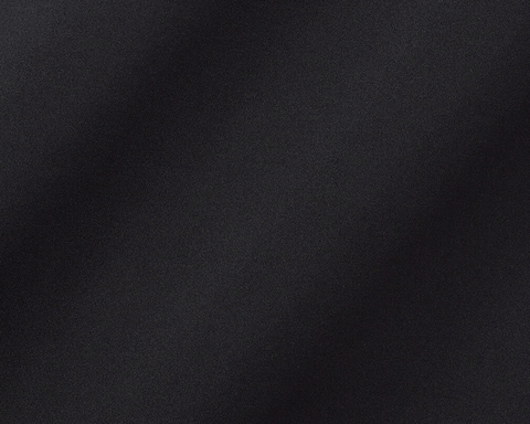 The Farrell Shirt: Black, close-up of textured performance jersey fabric with subtle folds, featuring long sleeves, spread collar, and contrast piping for versatile comfort and style.
