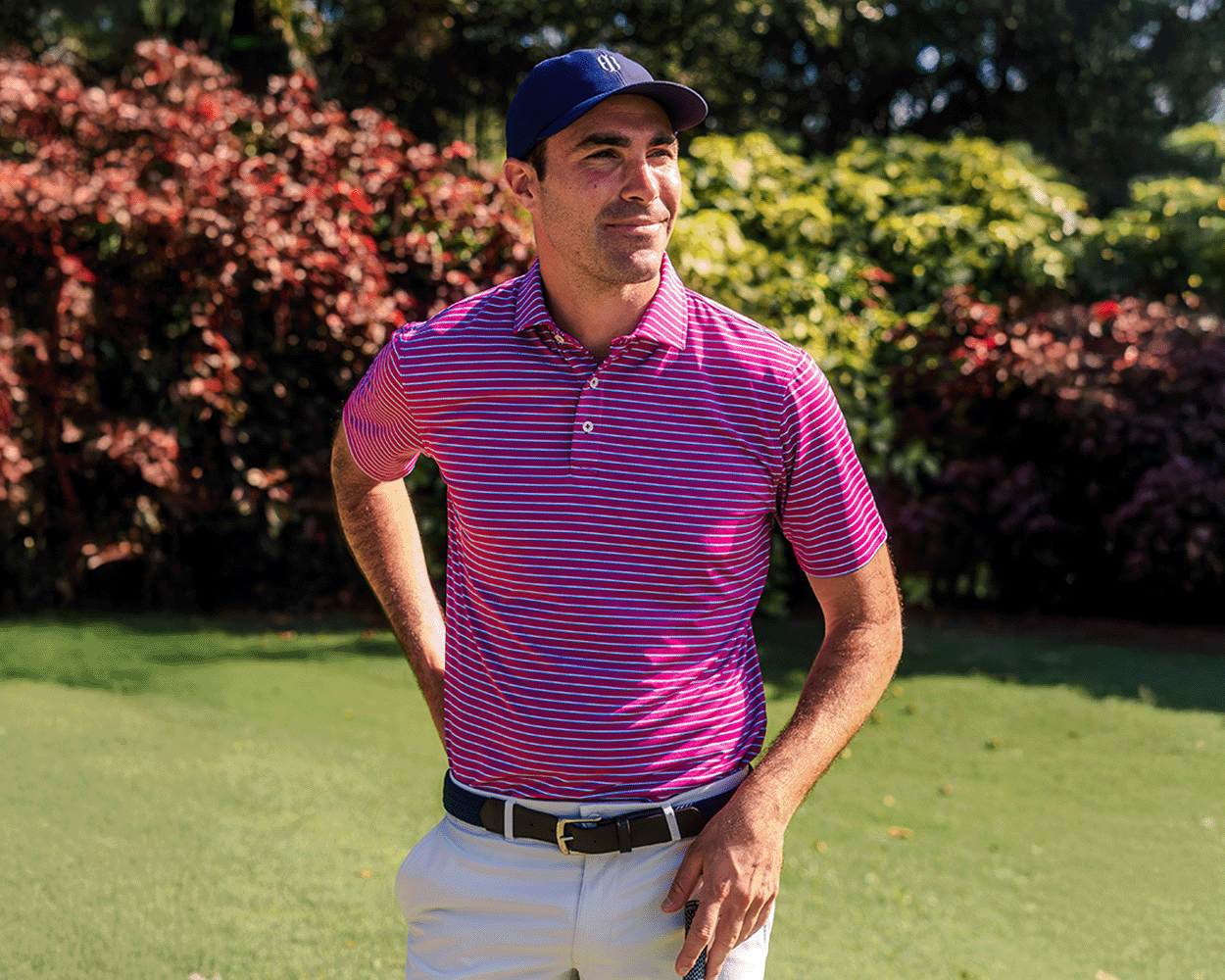 A man on a golf course wears The Springer Shirt, showcasing its breathable fabric, moisture-wicking features, and distinctive spread collar, while holding a golf club.