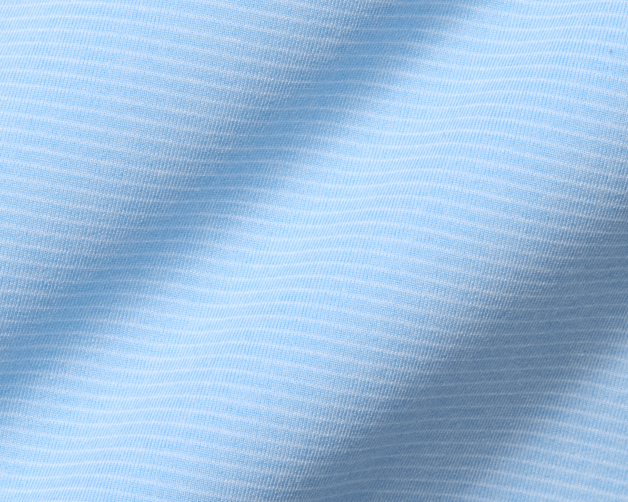 Close-up of The Holland Shirt: Heathered Vista Blue, showcasing its light-blue knit fabric with fine horizontal stripes and visible texture, emphasizing its sophisticated design.