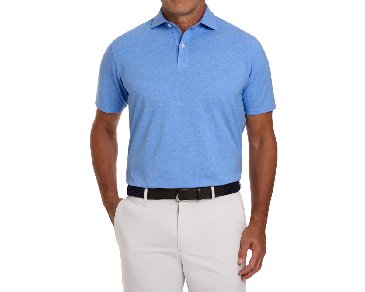 Model wearing The Hatcher Shirt in Horizon Blue, a short-sleeve polo made of soft Peruvian Pima cotton, tucked into light trousers with a dark belt.