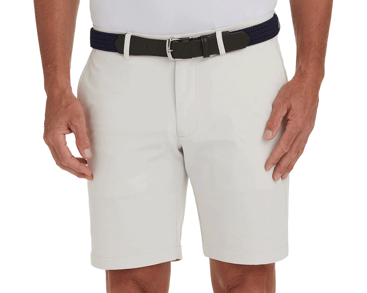 The Harwood Short: Stone, featuring a non-slip waistband and ball-marker pocket, worn with a dark navy belt, offers classic style and performance.