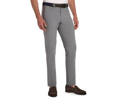 The McDaniel 5 Pocket Pant: Light Gray, slim-fit, worn with a dark woven belt and brown suede loafers, showcasing wrinkle-resistant, quick-dry fabric with eco-friendly stretch.