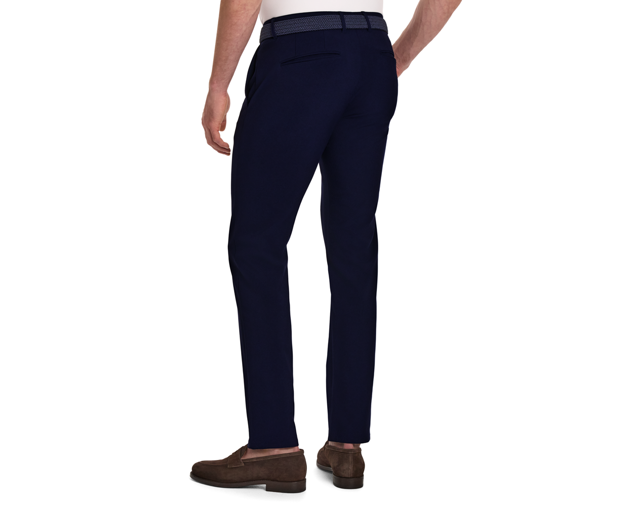 Back view of a male model wearing The Anson Chino Pant: Navy, showcasing slim fit with slant pockets, woven belt, and brown loafers.
