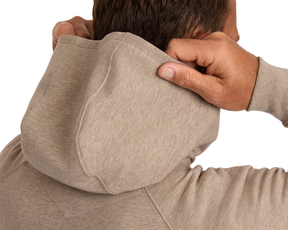 The Lawson Hoodie: Heathered Dune, shown from the back, features a light-beige design without drawstrings, highlighting its ultra-soft fabric as the wearer adjusts the hood.
