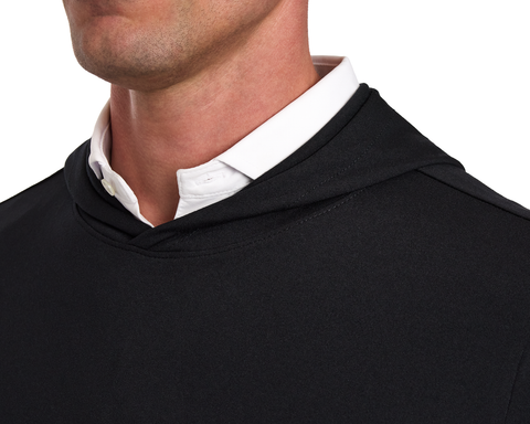 The Jackson Hoodie: Black, showcased over a white button-down shirt, features a sleek, lightweight design without drawstrings or pouches, perfect for golf.