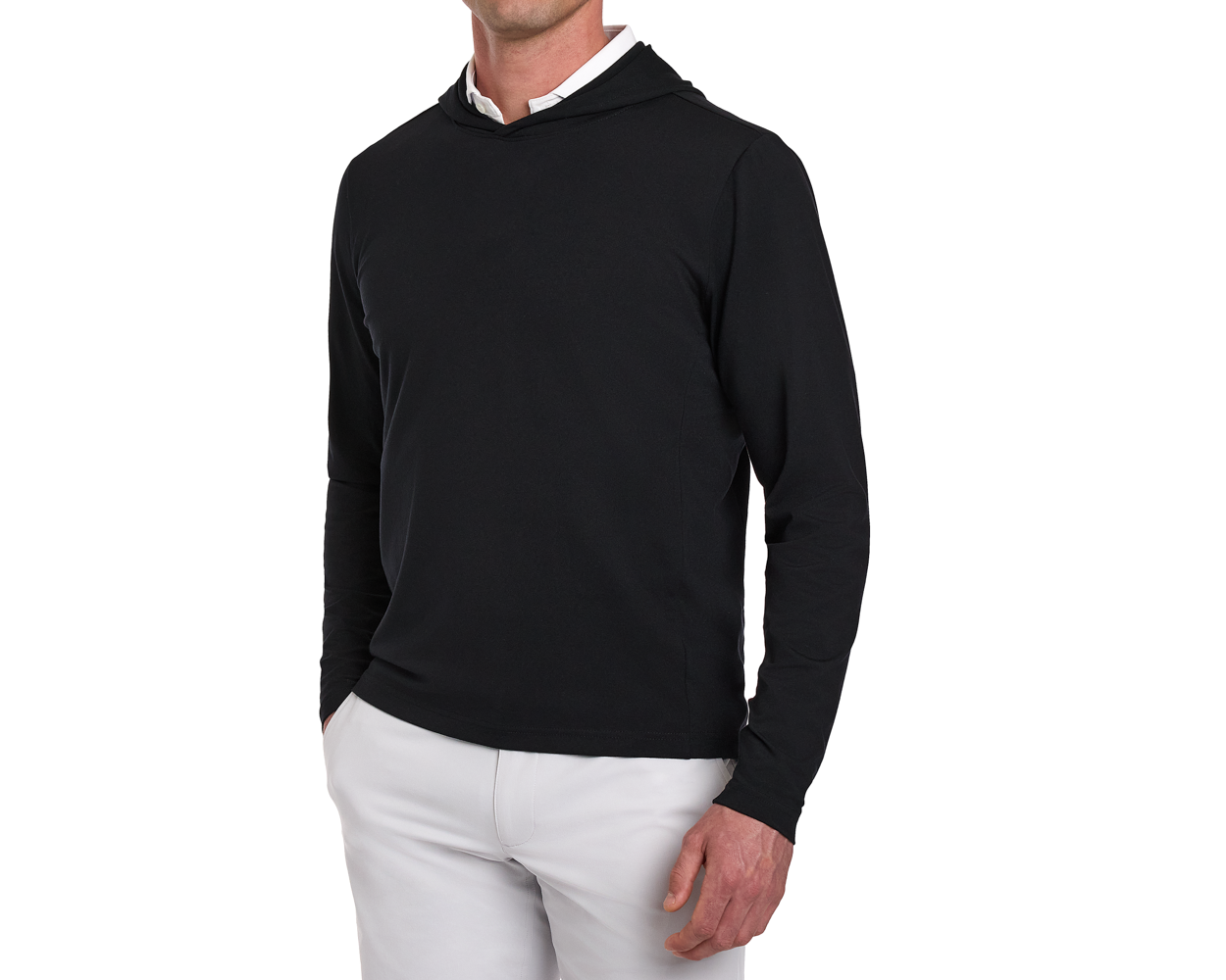 Male model wearing The Jackson Hoodie: Black over a white shirt, paired with light trousers, showcasing its streamlined design and soft performance fabric.
