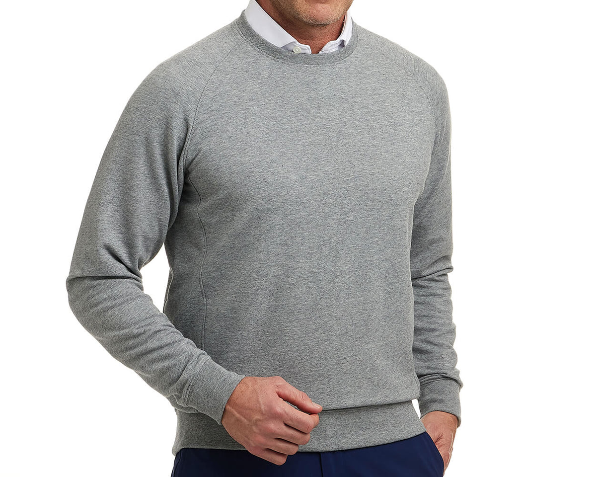 Man wearing The Kennedy Crewneck: Heathered Gray, a light-gray crewneck sweatshirt with a plush terry interior, over a white shirt, paired with dark pants.