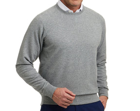 Man wearing The Kennedy Crewneck: Heathered Gray, a light-gray crewneck sweatshirt with a plush terry interior, over a white shirt, paired with dark pants.