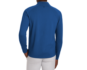The Stuart Quarter-Zip: Maidstone Blue top showcases a fold-over collar, subtle back logo, paired with gray trousers, highlighting performance fabric and versatile style.