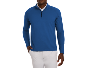 Model wearing The Stuart Quarter-Zip: Maidstone Blue, a long-sleeve, textured rib pullover with a white shirt underneath, paired with light trousers.