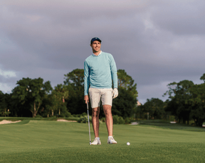 Man on golf course wearing The Laidlay Crewneck: Heathered Harbor, lining up a putt, showcasing its heathered texture and signature fit for mobility.