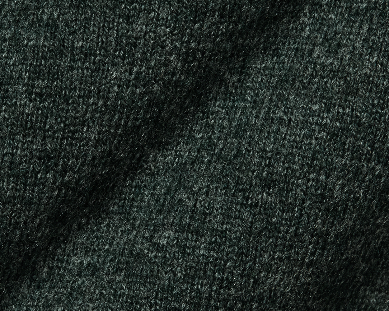 The Logan Hoodie Sweater: Heathered Ivy, showcasing a close-up of its intricate woolen knit texture, highlighting the luxurious Merino and cashmere blend's softness and warmth.