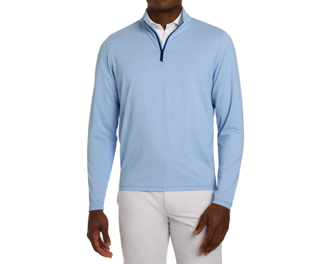 The Bell Quarter-Zip: Heathered Vista Blue, worn over a white collared shirt with light-gray trousers, features a modern drop-tail silhouette and sporty sophistication.