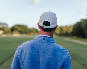 Person in a backward cap and light blue Sullivan Quarter-Snap pullover on a golf course, showcasing its quilted insulation and casual style.
