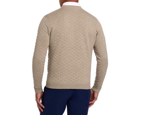 The Ward Crewneck Sweater: Heathered Light Dune, rear view; diamond-quilted pattern, ribbed cuffs, worn with dark navy pants by male model.