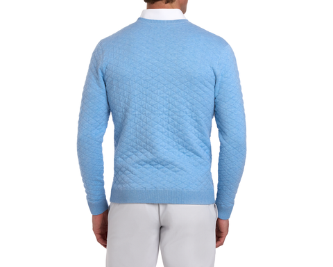 The Ward Crewneck Sweater: Heathered Vista Blue features a diamond-quilt pattern, shown on a man over a white shirt, paired with gray pants.