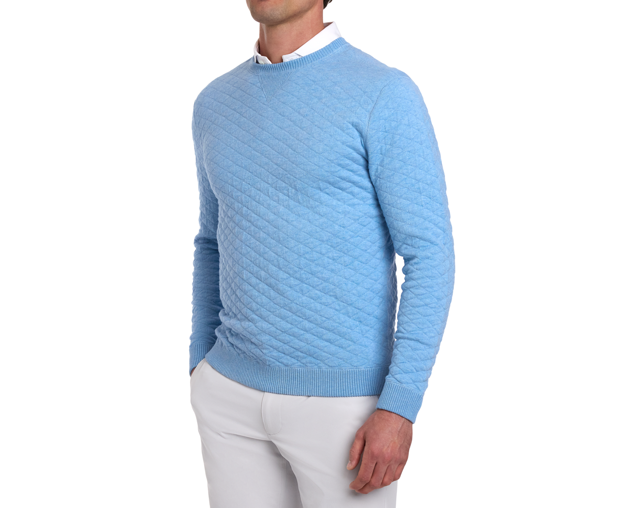 Model wearing The Ward Crewneck Sweater: Heathered Vista Blue, featuring a quilted diamond pattern, over a white collared shirt with light trousers.