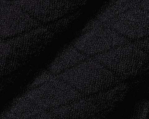Close-up of The Wallace Hoodie Sweater: Black, showing intricate knit stitches and folded fabric, highlighting its 100% Egyptian cotton texture and ribbed side panels.