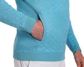 Person wearing The Wallace Hoodie Sweater: Heathered Harbor, a diamond-quilted pullover with ribbed cuffs, hem, and a kangaroo-style pocket, hand tucked inside.