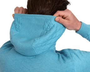 Person lifting hood of The Wallace Hoodie Sweater: Heathered Harbor, showcasing its ribbed side panels and premium Egyptian cotton fabric for warmth and style.