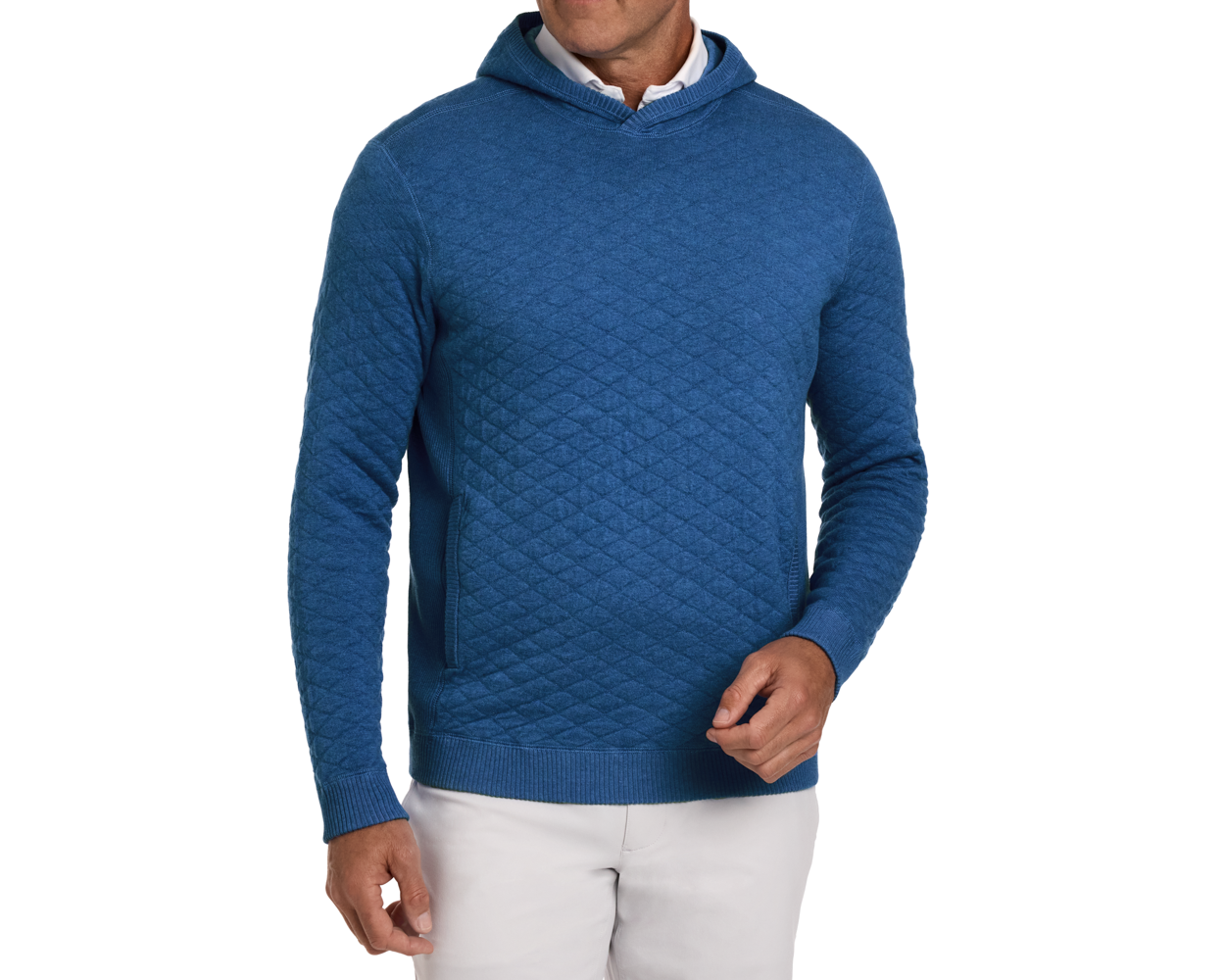 The Wallace Hoodie Sweater in Heathered Maidstone Blue, featuring a quilted pattern, ribbed cuffs, and hem, worn over a white shirt with light trousers.