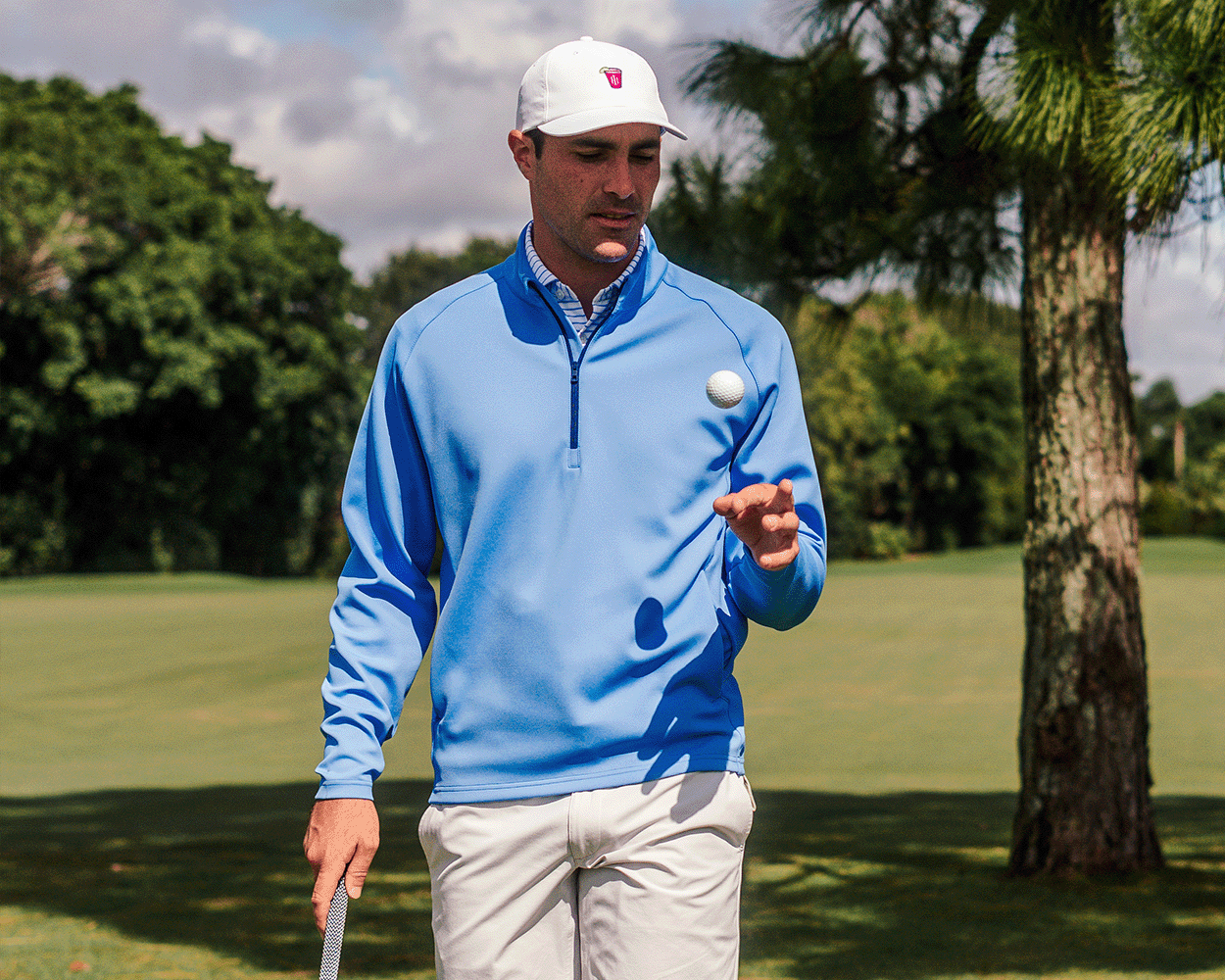 Man on golf course wearing The Rodgers Quarter-Zip: Horizon Blue, holding a golf club, showcasing its stretchy, midweight design ideal for golf or casual wear.