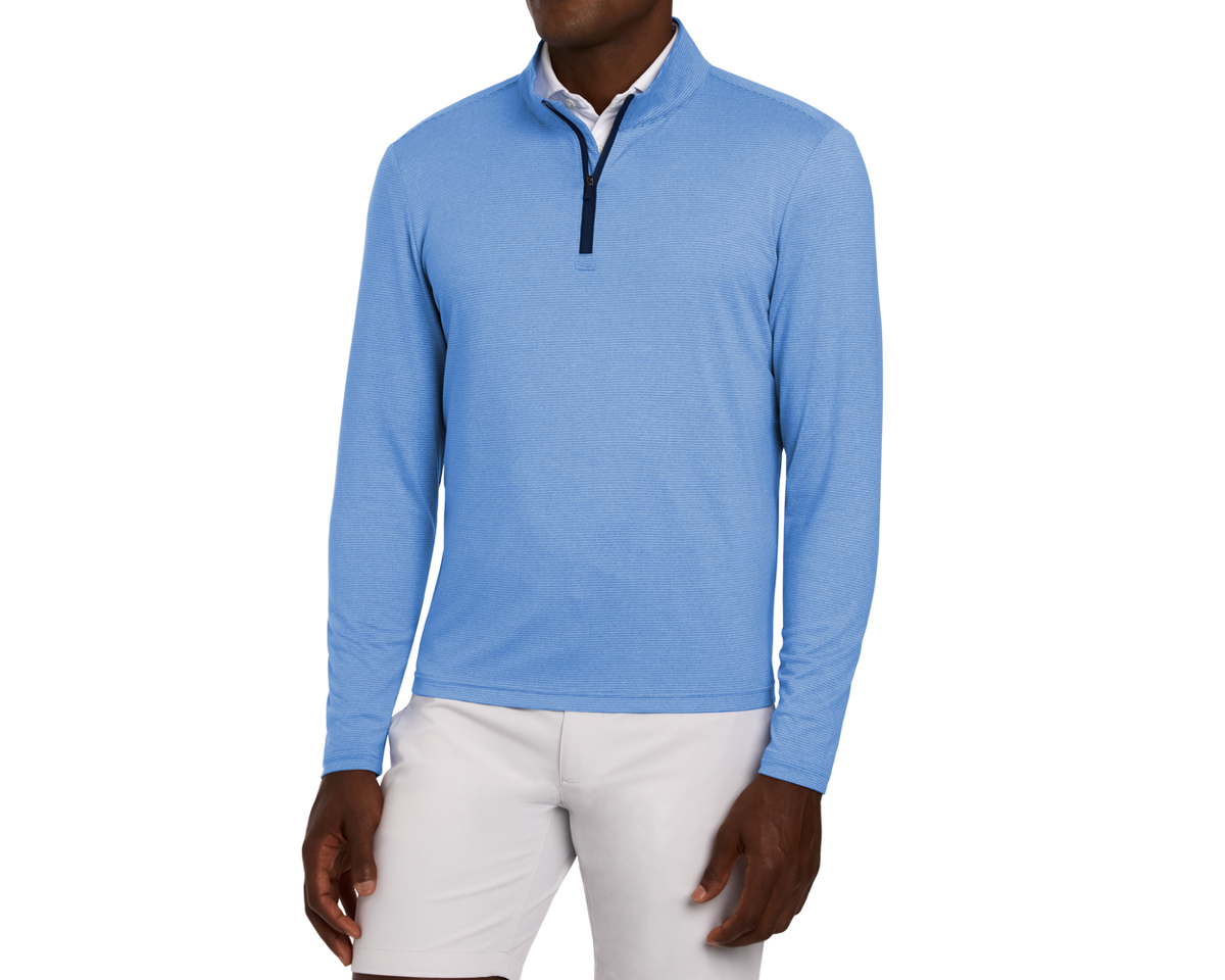 Male model wearing The Royce Quarter-Zip in Heathered Horizon Blue over a white shirt, paired with light trousers. The sporty-casual pullover features a darker zipper placket.