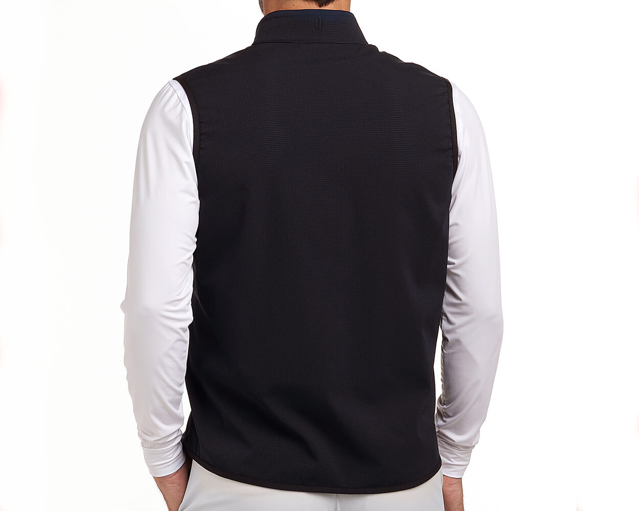 Back view of The Ventura Vest: Black, showcasing its sleeveless design over a white top, highlighting ultralight, breathable fabric with hidden zippered pockets.