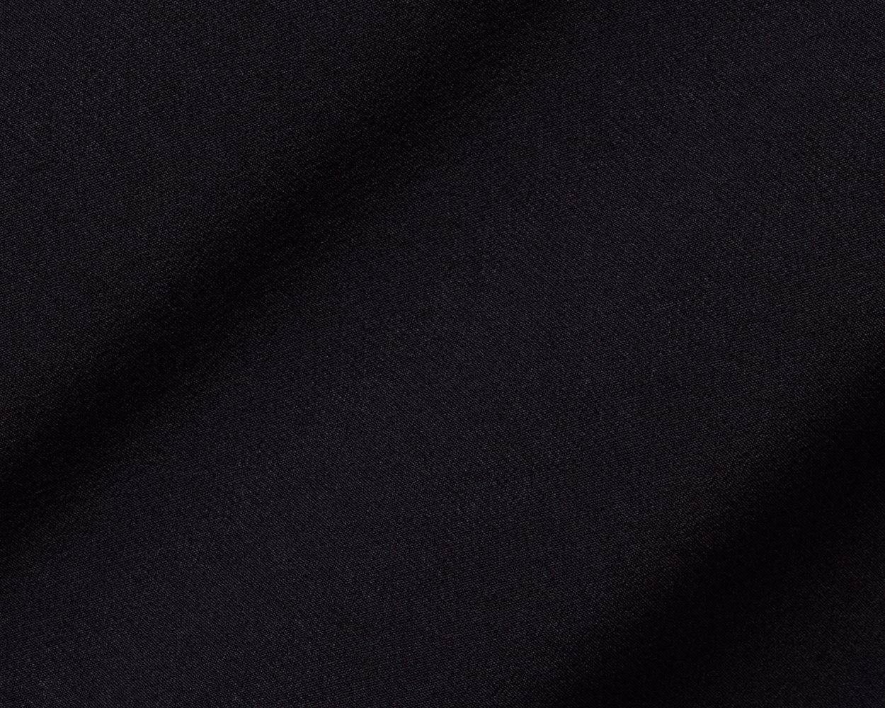 Close-up of The Boyd Vest: Black fabric, showcasing its fine woven texture and soft folds, highlighting the vest's windproof and water-resistant qualities.