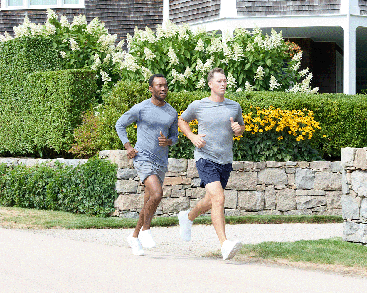 Two men jogging, one wearing The Carr T-Shirt: Heathered Navy, highlighting its fit and comfort with moisture-wicking and stretch features.