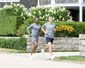 Two men jogging, one wearing The Carr T-Shirt: Heathered Navy, highlighting its fit and comfort with moisture-wicking and stretch features.