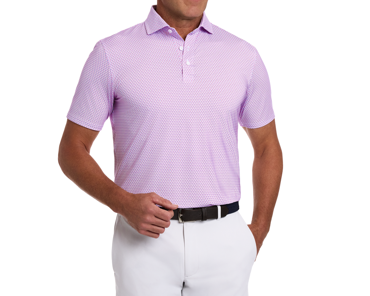 Man wearing The Justice Shirt: Horizon Blue & Cabernet, a light purple micro-patterned polo, tucked into white trousers with a dark belt, showcasing style and performance features.