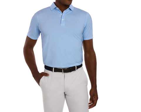 The Hanover Shirt: Maidstone Blue, a light-blue polo with geometric pattern, short sleeves, offers four-way stretch, moisture-wicking, UPF 50+ protection; styled with gray trousers.