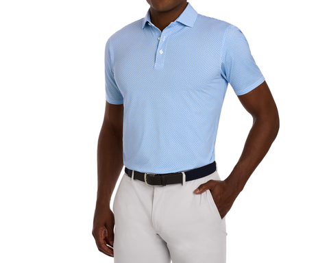 Man wearing The Hanover Shirt: Maidstone Blue, featuring a geometric jet pattern, short sleeves, tucked into gray trousers with a dark belt.