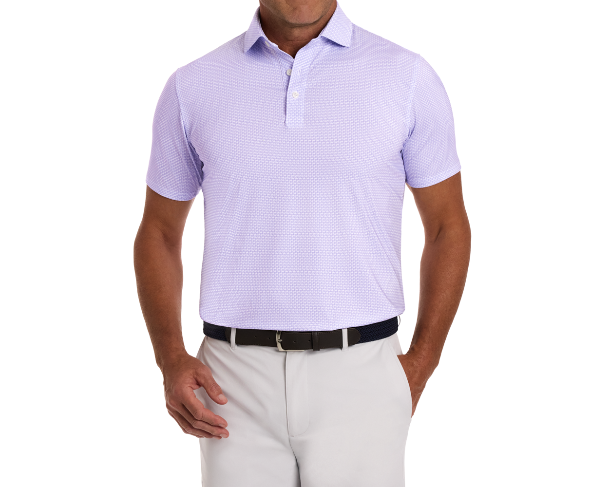 The Hanover Shirt: Tudor, a light lavender polo with a subtle texture, worn tucked into light trousers, featuring a dark woven belt and metal buckle.