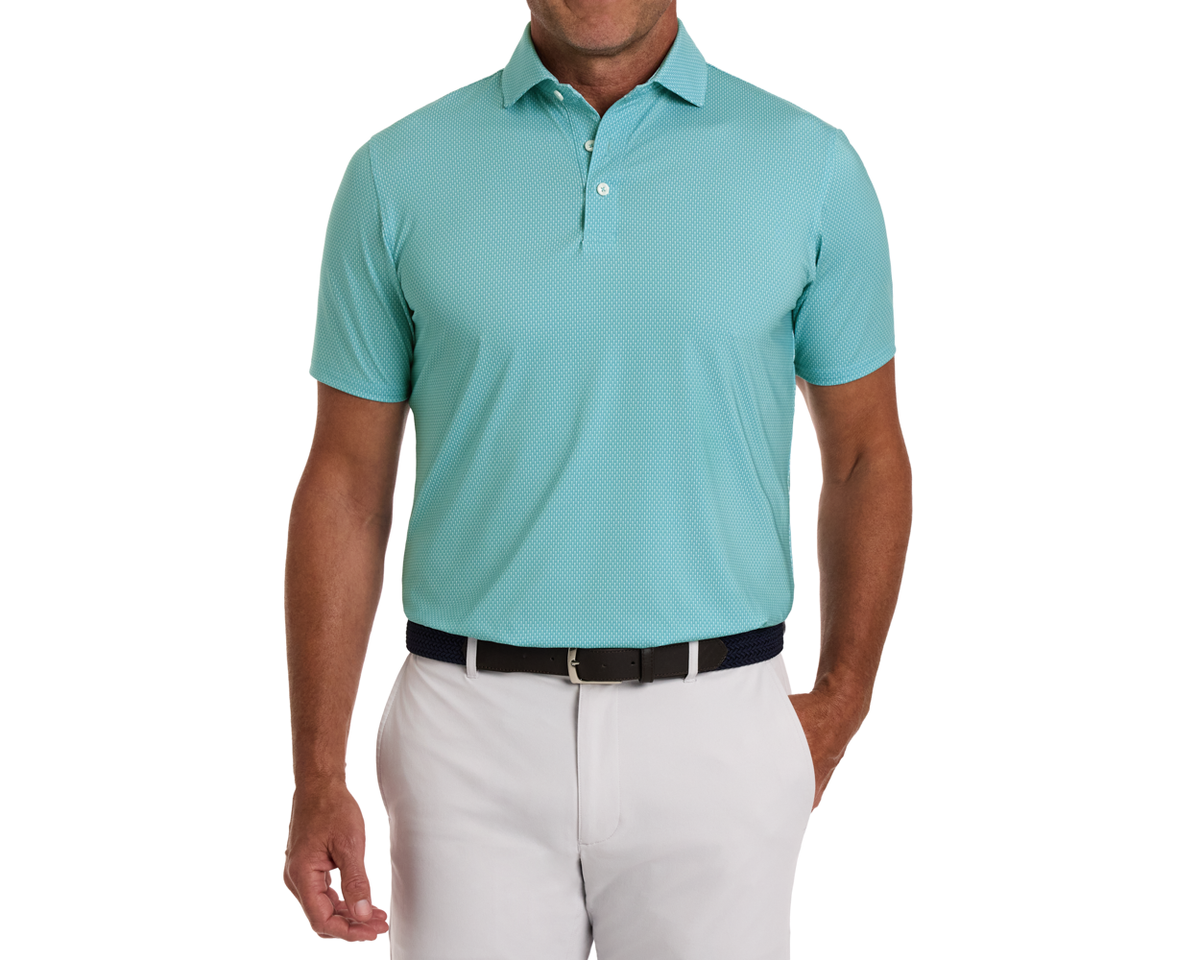 Man wearing The Hicks Shirt: Harbor, a short-sleeve polo with geometric pattern, tucked into light pants, featuring a woven belt.