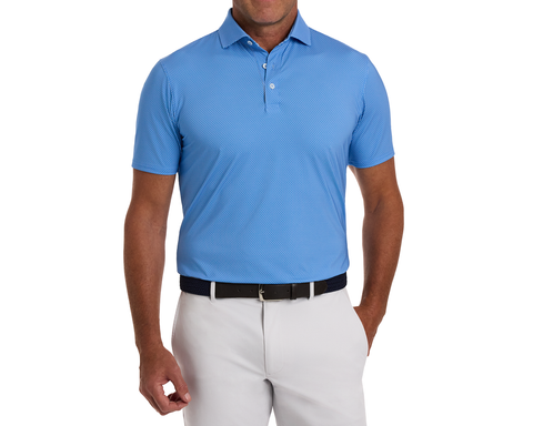 The Hicks Shirt: Horizon Blue on model, showcasing its geometric golf-tee pattern, structured collar, and stylish fit, paired with light-gray trousers and a dark woven belt.