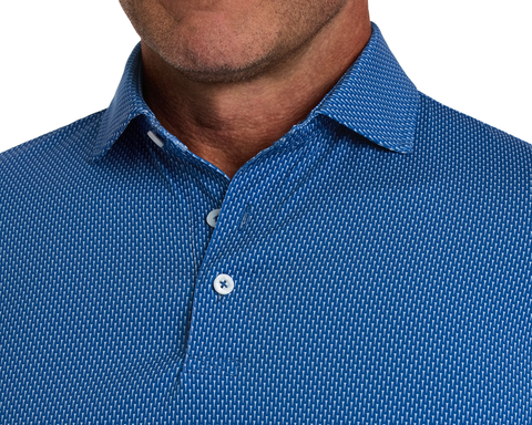 The Hicks Shirt: Maidstone Blue features a geometric pattern, pointed collar, and two white buttons, crafted for performance with moisture wicking and sun protection.
