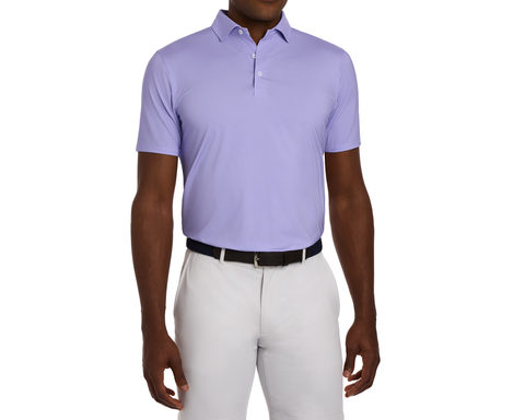 The Hicks Shirt: Tudor, featuring a geometric golf-tee pattern, spread collar, and performance jersey, worn tucked into trousers with a dark woven belt.