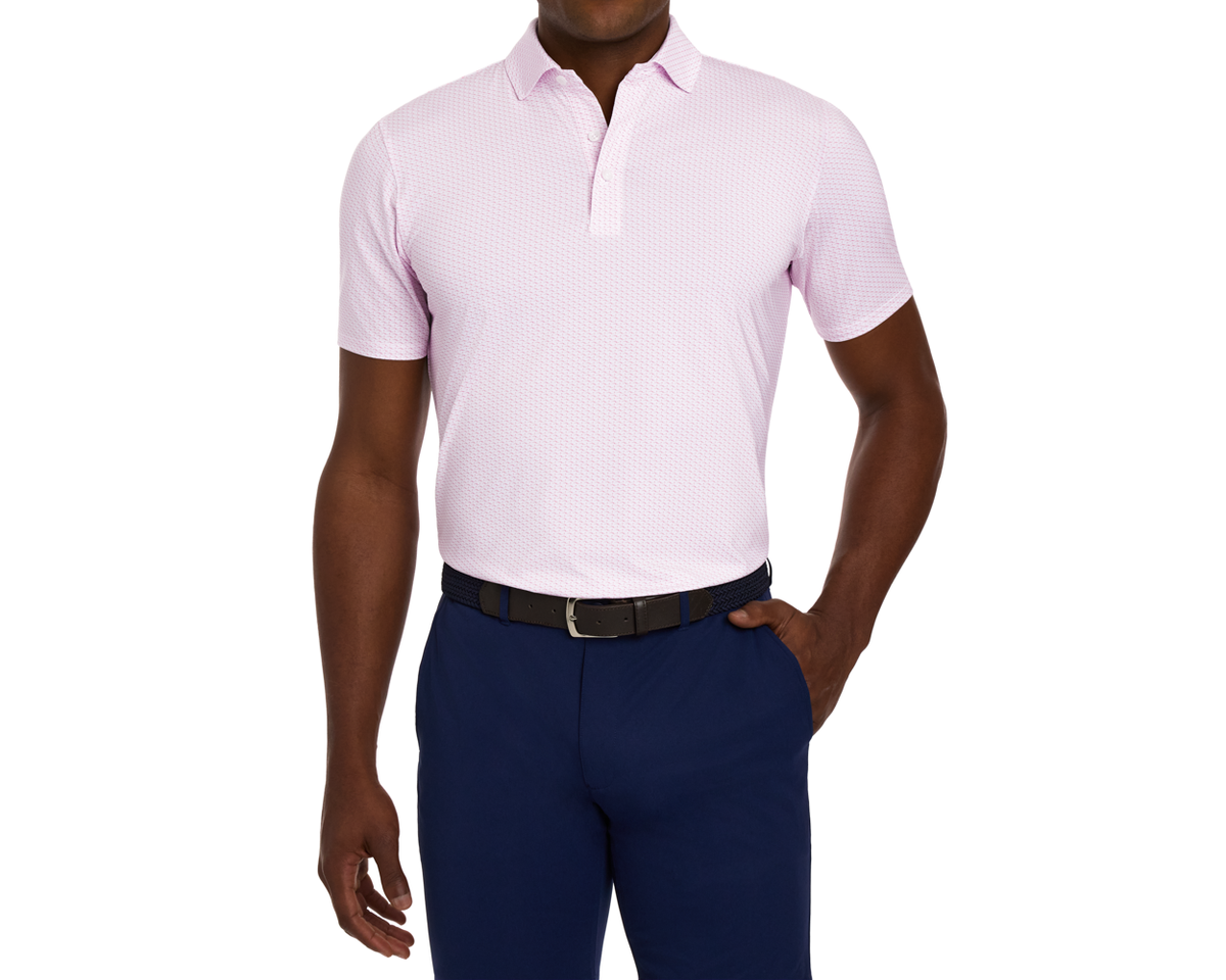 Model wearing The Atwood Shirt: Belmont, a light-pink short-sleeve polo with a structured spread collar, paired with dark navy trousers and a woven belt.