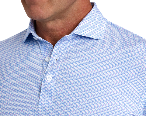 The Fulton Shirt: Belmont & Horizon Blue features a white polo with blue thumbs up print, showcasing a structured collar and performance jersey fabric.