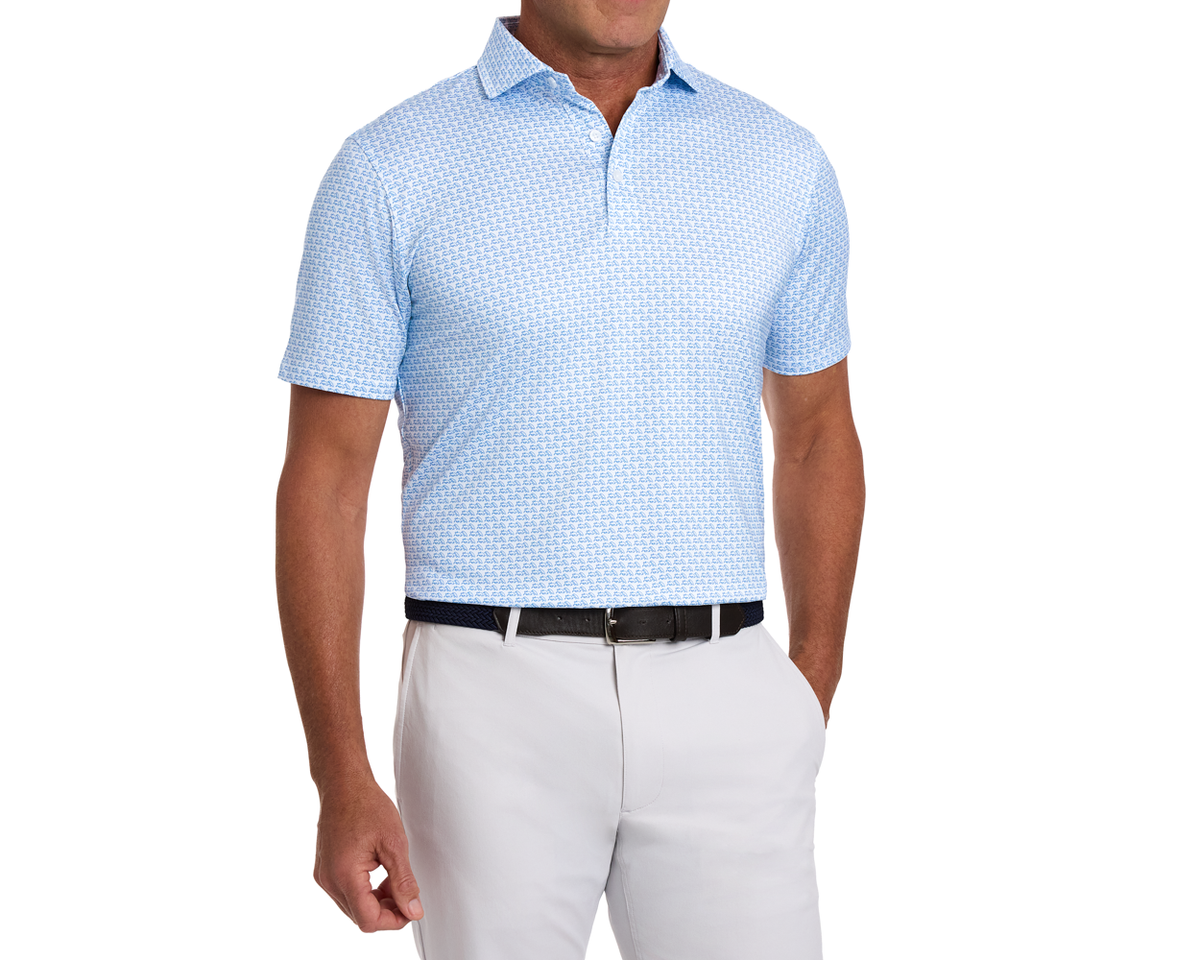 Male model wearing The Berkeley Shirt: Maidstone Blue, a light-blue polo with bull-and-bear motif, tucked into light trousers with woven belt.