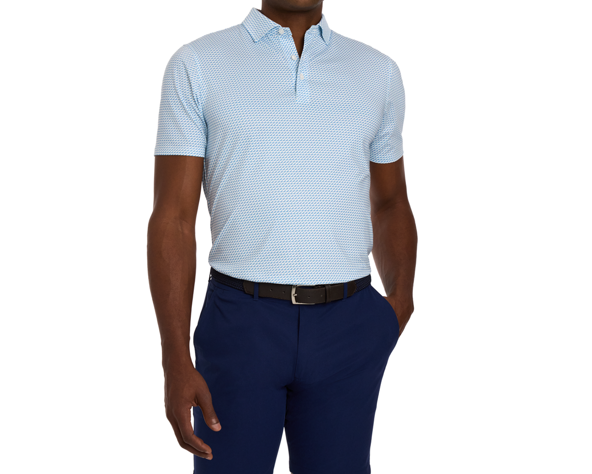 Man wearing The Walton Shirt: Maidstone Blue, a light-blue polo with geometric print, tucked into navy trousers, showcasing AIRATION® fabric's breathability and comfort.