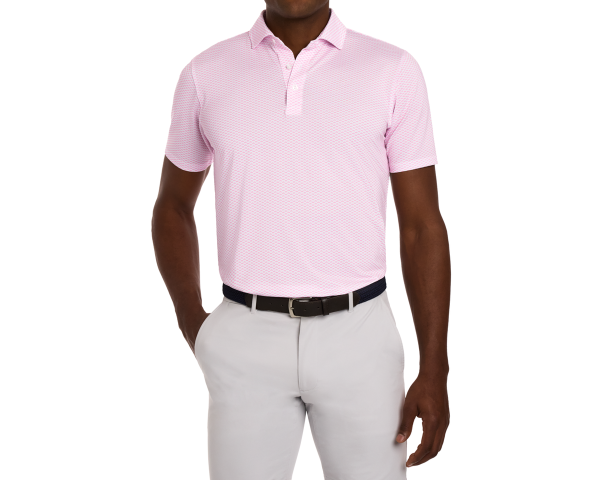 Man wearing The Geiger Shirt: Belmont, a short-sleeve polo with geometric pattern, tucked into light gray trousers with a dark belt.