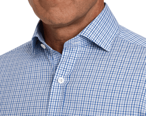 Person wearing The Wright Shirt: Vista Blue with a blue-and-white gingham pattern, unfastened top button, showcasing its crisp, breathable fabric and structured spread collar.