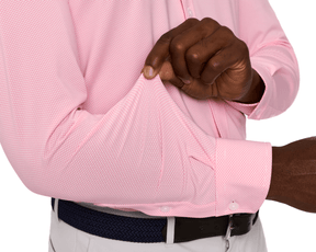 Person wearing The Goodrich Shirt: Belmont in pink, showcasing its stretch and drape, with a geometric pattern, tucked into light trousers with a belt.