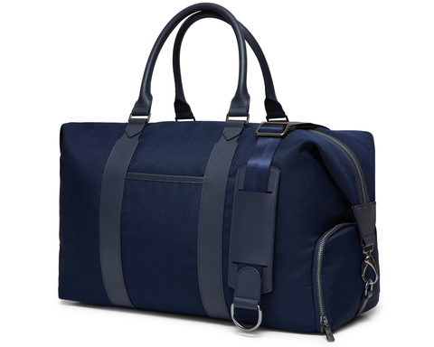 The Byers Duffel Bag: Navy Ballistic, featuring a canvas build with leather-trimmed handles, detachable shoulder strap, top zip closure, and an external zip pocket.