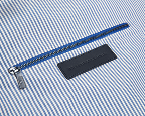 The Byers Duffel Bag: Navy Ballistic, featuring blue-and-white pinstripe interior, metal zipper, and embossed leather brand patch, showcasing its sleek interior zip pocket.